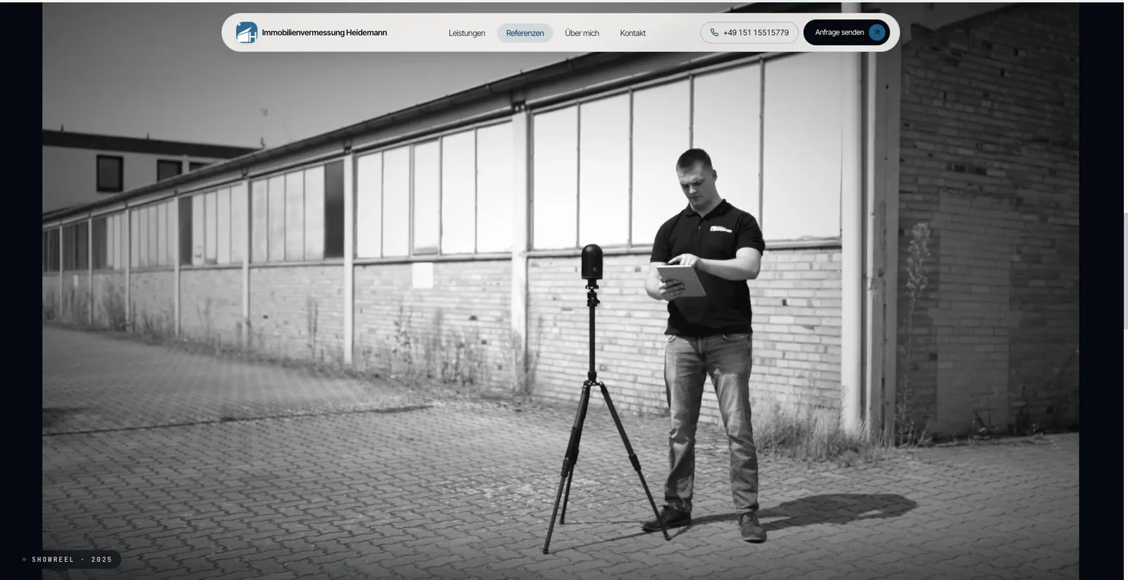 Immobilienvermessung Heidemann: Schwarzweissbild aus dem Showreel, Vermessung mit einem Laserscanner auf dem Stativ vor einer Halle