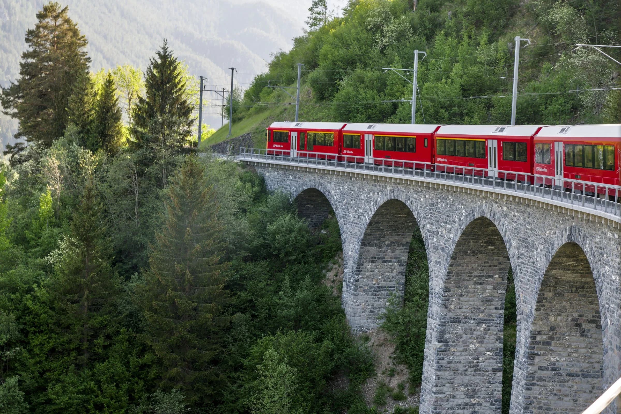Roter Zug auf dem Viadukt in den Alpen