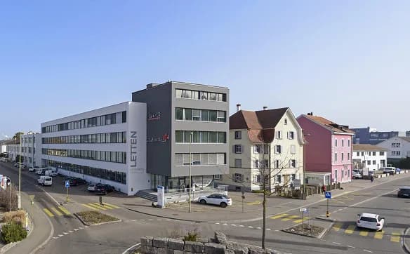 Street view of the Letten office building in Allschwil, next to it the older houses at the crossing