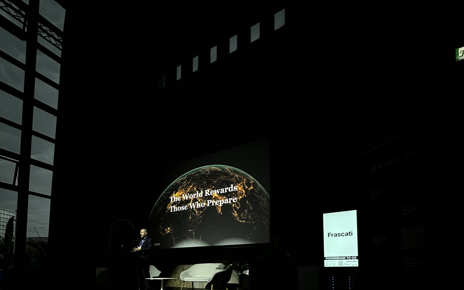Dunkler Saal der Voltahalle mit Redner vor einer Leinwand, auf der The World Rewards Those Who Prepare steht, rechts die Powerbank Station von Frascati